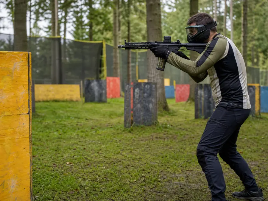 Airsoft player in full kit moving through woodland