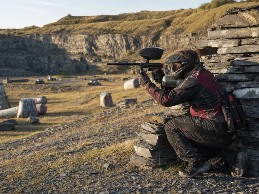 Paintball players taking cover behind barrels in the quarry arena